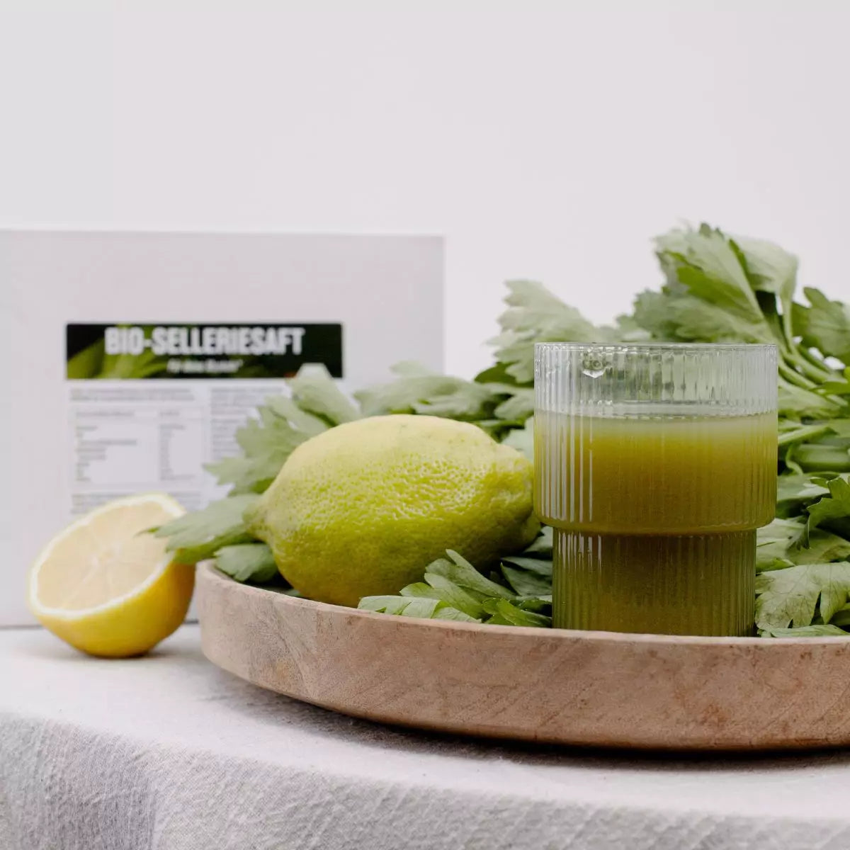 Glas mit Selleriesaft und Sellerie im Hintergrund